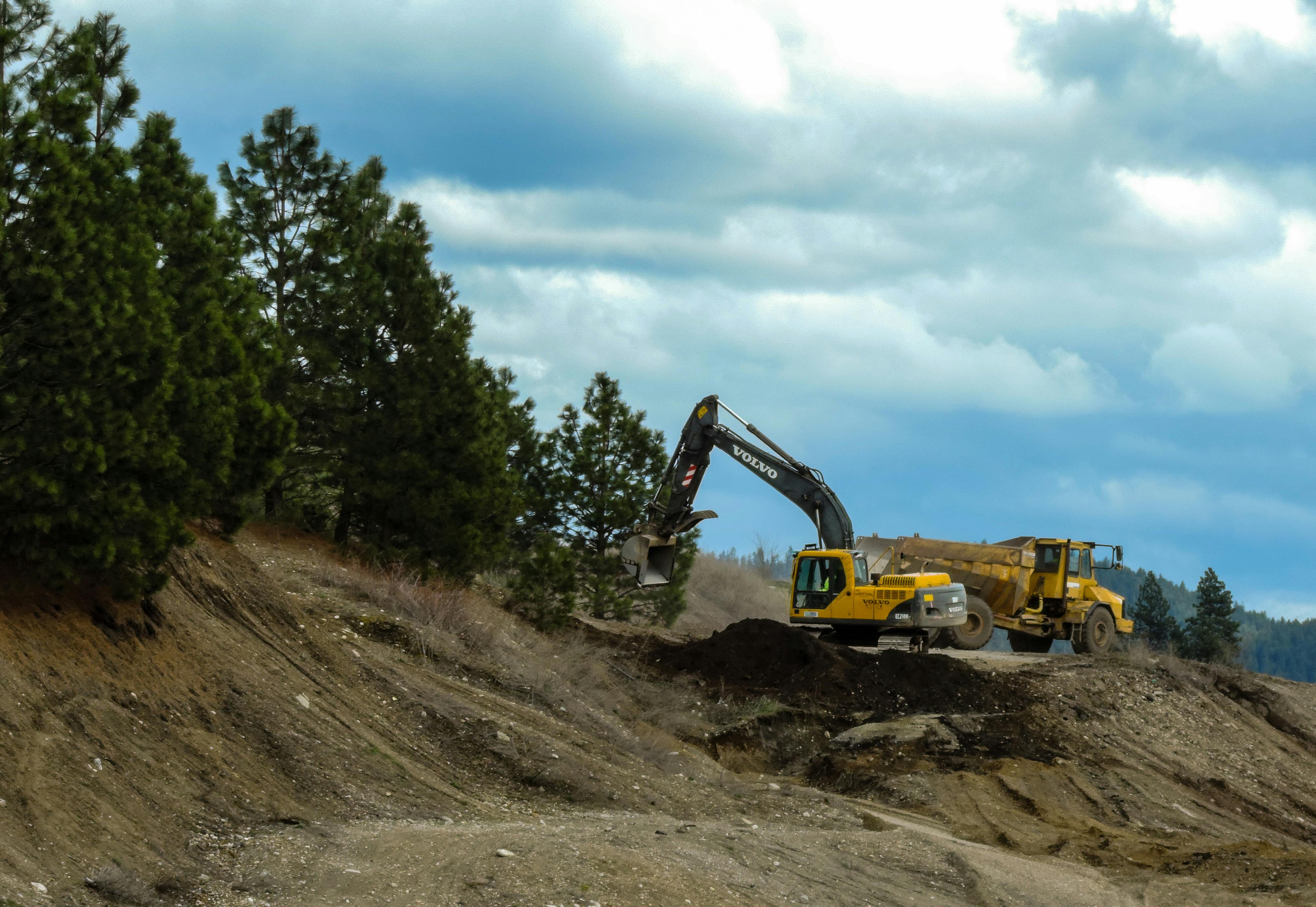 Excavator and truck working at a construction site in Coeur d'Alene, Idaho with cloudy skies.